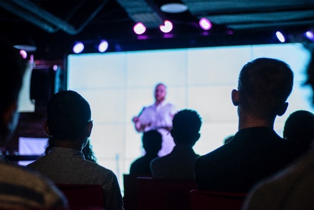 A group of people watching a speaker on a stage.